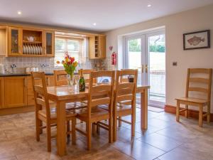 a kitchen with a wooden table with chairs and a dining room at Willow Cottage-Uk2788 in Penmaen-mawr