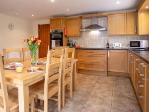 a kitchen with a wooden table and wooden cabinets at Willow Cottage-Uk2788 in Penmaen-mawr