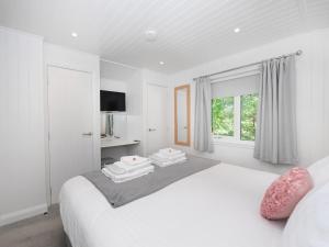 a white bedroom with a bed and a window at Clyde View in Langbank