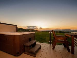 a hot tub on a deck with a table and a chair at Clyde View in Langbank