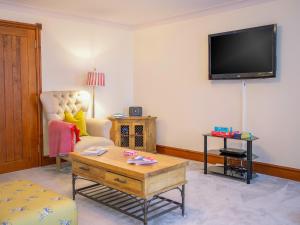 a living room with a couch and a tv on the wall at Willow Cottage-Uk2788 in Penmaen-mawr +17 photos