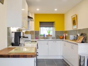 a kitchen with white cabinets and a yellow wall at Dutch Barn One - Uk12872 in Brynkir