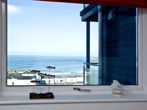 a window with a view of the ocean and a bird at 42 Ocean 1 in Crantock