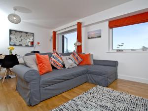 a living room with a gray couch with orange pillows at 42 Ocean 1 in Crantock +13 photos