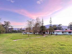 a field with a house in the background with a sunset at MERs house enjoys nature in Cajamarca