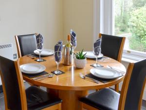 a wooden table with plates and wine glasses on it at Carnethic House - One Acre View in Fowey
