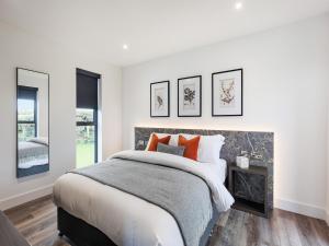 a white bedroom with a large bed with orange pillows at Cefni Lodge 1 - Uk42796 in Llangefni