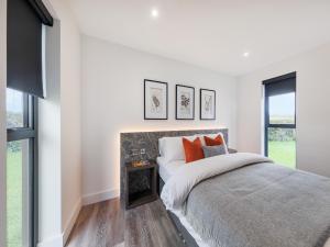a white bedroom with a bed and a window at Cefni Lodge 1 - Uk42796 in Llangefni