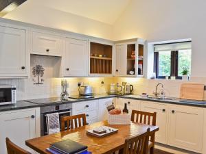 a kitchen with white cabinets and a wooden table at Paper Mill Cottage in Sutton
