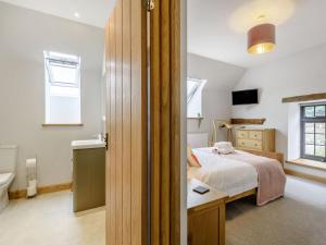 a bedroom with a bed and a toilet and a sink at Penshenkin Barn in Llanfihangel-nant-Melan
