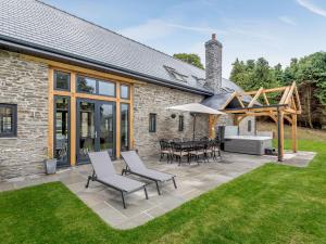 a patio with a table and chairs and a building at Penshenkin Barn in Llanfihangel-nant-Melan