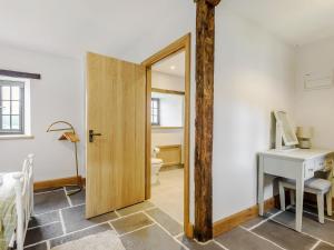 a room with a door leading to a bedroom with a desk at Penshenkin Barn in Llanfihangel-nant-Melan