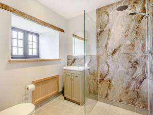a bathroom with a shower and a toilet and a sink at Penshenkin Barn in Llanfihangel-nant-Melan +28 photos