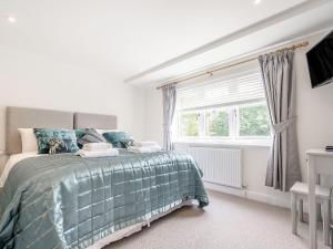 a bedroom with a bed with a green comforter and a window at Pennyard House in Banwell