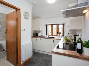 a kitchen with white cabinets and a clock on the wall at Daisy Cottage - Uk31294 in Locking