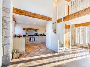 a kitchen with white cabinets and wooden beams at Badger Hill Barn in Malham