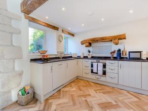 a kitchen with white cabinets and a wooden floor at Badger Hill Barn in Malham +17 photos