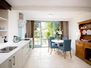 a kitchen with a table with blue chairs and a table at The Hall - Uk32690 in Horton