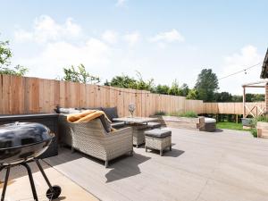 a patio with a grill and chairs and a table at Silhouette's Stable - Uk34102 in Chichester