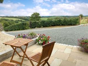 a wooden table and chairs on a patio with flowers at Trezeal Barn in North Hill