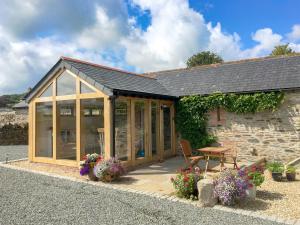 a house with a conservatory with flowers in front of it at Trezeal Barn in North Hill