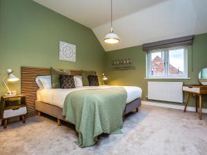 a green bedroom with a bed and a window at The Hazels - Ukc4614 in Dunholme +3 photos