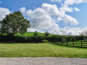 a field with a fence and a tree on a hill at Swiss Cottage in Lancaster