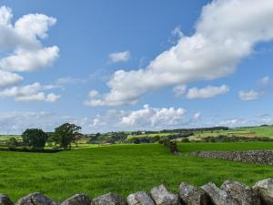 a field of green grass with a blue sky and clouds at Swiss Cottage in Lancaster