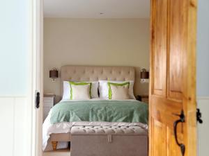 a bedroom with a bed with green sheets and pillows at Grapevine Cottage in Stocklinch