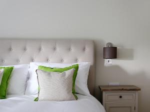 a white bed with green and white pillows at Grapevine Cottage in Stocklinch +12 photos