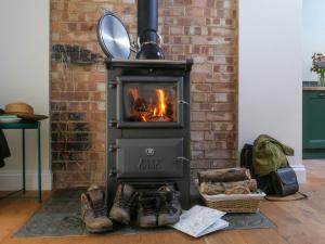 a stove with a fire in a brick wall at The Stables - Uk50804 in Halesworth