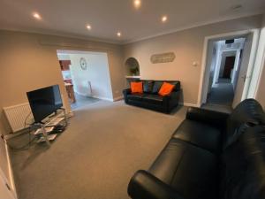 a living room with a black couch and a television at West Lodge - Uk7137 in Newton Stewart