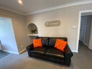 a black leather couch with orange pillows in a living room at West Lodge - Uk7137 in Newton Stewart