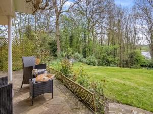 a patio with two chairs and a table in a garden at Dunburgh Wood in Beccles