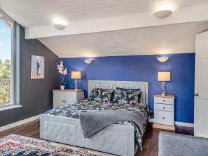 a blue bedroom with a bed and two lamps at Dunburgh Wood in Beccles