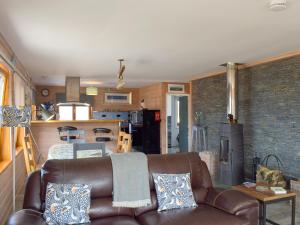 a living room with a leather couch and a kitchen at Seal Rocks in Lendalfoot