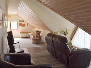 a living room with leather chairs and a staircase at Seal Rocks in Lendalfoot
