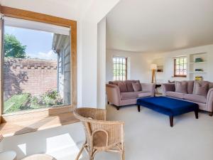 a living room with two couches and a large window at Wittle Cottage in Quidenham