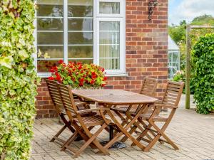 a wooden table with two chairs and a pot of flowers at Henrys Retreat in Ingoldsby