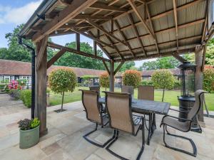 a wooden pergola with a wooden table and chairs at The Barn - Uk49371 in Send