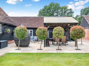 a patio with chairs and trees in front of a house at The Barn - Uk49371 in Send