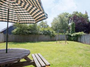 a picnic table with an umbrella and a swing at Swallows Cottage in Parkham