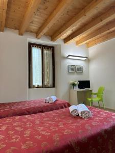 a bedroom with two beds with red sheets and a window at Locanda Graziella in Moerna
