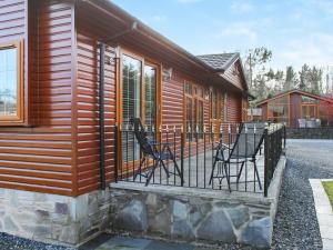 a house with a deck with chairs on it at Stag Lodge in Auchterarder
