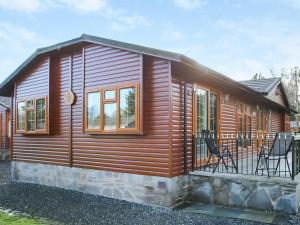 a log cabin with a deck and chairs at Stag Lodge in Auchterarder