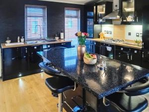 a kitchen with black counters and a large island with bar stools at Stag Lodge in Auchterarder