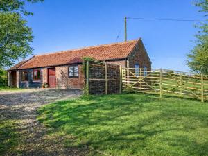 an old brick house with a wooden fence at The Barn in Cantley