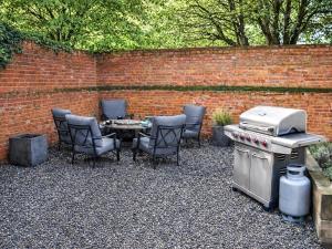 a patio with a table and chairs and a grill at South Barn in Heydon
