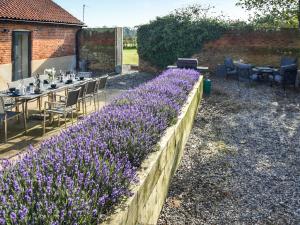 a garden with purple flowers and tables and chairs at South Barn in Heydon