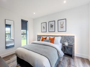a white bedroom with a large bed with orange pillows at Cadnant Lodge 2 - Uk42795 in Llangefni